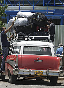 Dos cubanos cargan un coche en el aeropuerto habanero. | Reuters.