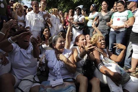 Damas de Blanco, en el suelo, rodeadas por partidarios del Gobierno. | Reuters