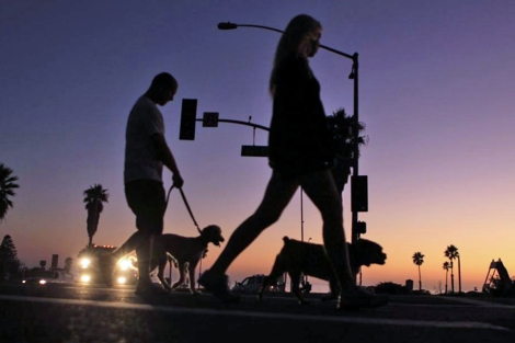 Una pareja pasea a sus perros casi a oscuras en Cardiff, California. | Reuters