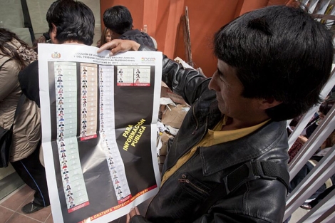 Un hombre muestra un cartel informativo para las elecciones de este domingo. | Efe