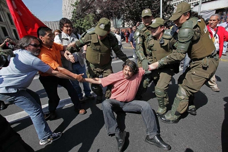 Un manifestante es detenido por la Policía cerca al Palacio de La Moneda. | AP