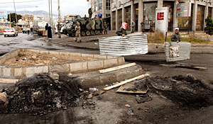 Dos trabajadores limpian las calles donde se produjeron los principales enfrentamientos. EFE