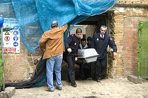 Una parjea de la Policia Nacional saca el féretro de un trabajador que falleció tras caer desde un andamio en Cádiz. (Foto: EFE)