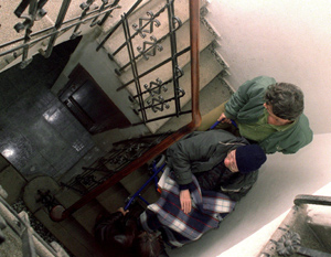 Imagen de archivo de un anciano discapacitado que es ayudado para bajar la escalera de su vivienda (Foto: EFE).