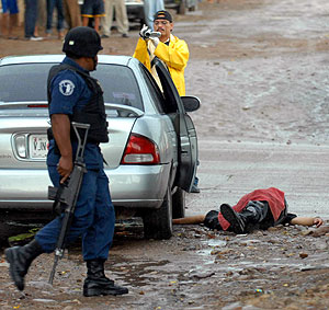 Un policía patrulla junto al cadáver de un hombre asesinado. (Foto: EFE)