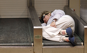 Una pasajera duerme en una cinta de un puesto de facturación. (Foto: Bernardo Díaz)