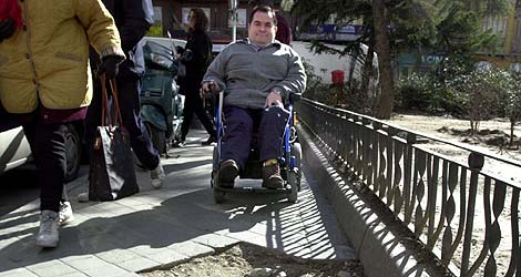 Un hombre en silla de ruedas intenta superar los baches de la acera. | José Ayma
