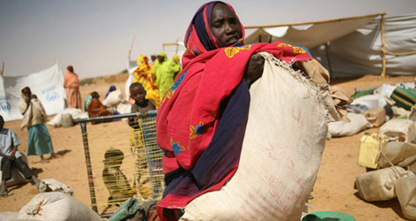 Una mujer carga con un saco de ayuda alimentaria. | ACNUR / H.Caux