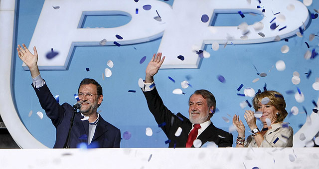 Mariano Rajoy saluda desde el balcón de Génova, junto a Jaime Mayor Oreja y Esperanza Aguirre. | Efe