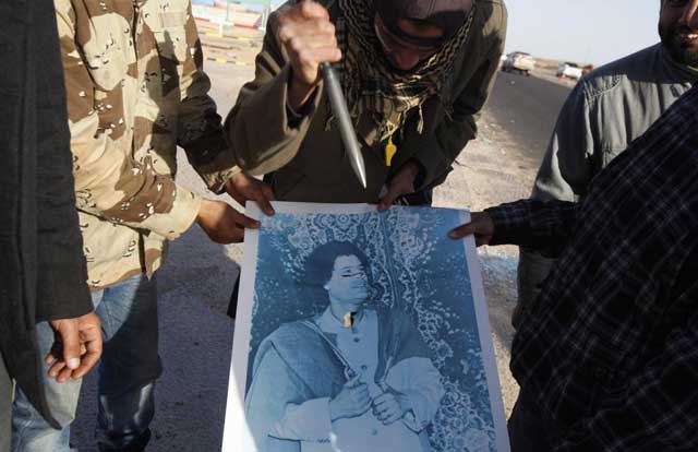 Un rebelde apuñala una imagen del coronel libio Muamar Gadafi. | Reuters Un rebelde apuñala una imagen del coronel libio Muamar Gadafi. | Reuters
