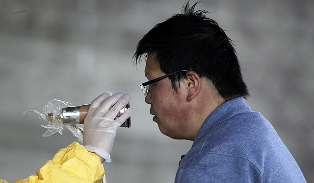 Un miembro del Ejército mide la radiación de un vecino de Fukushima. | Reuters
