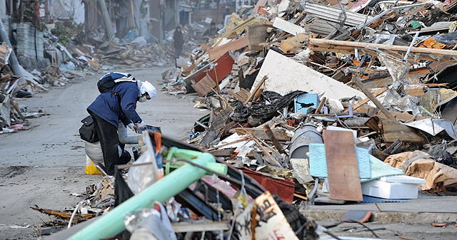 Un hombre busca entre los escombros de una casa. | Afp