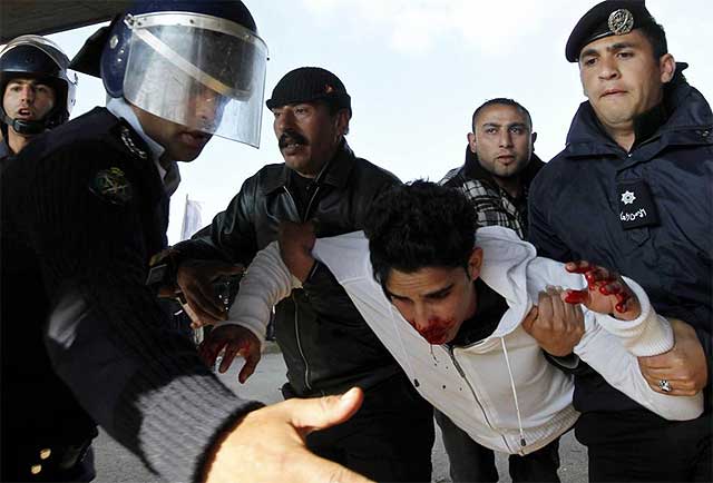 Un manifestante herido en Ammán, transportado por policías. | afp