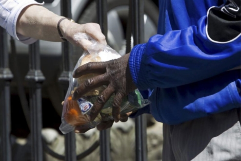 Un inmigrante recibe una bolsa de comida en Roma. | Efe