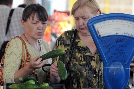Una mujeres miran unos pepinos en Mogilev, Bielorrusia.|