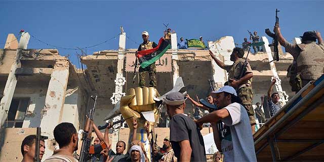 Un grupo de rebeldes celebran en Bab el Aziziya. | Reuters MÁS IMÁGENES