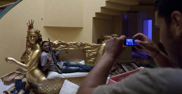 Un rebelde posa sentado en el sofá con forma de sirena en la residencia de Aisha Gadafi. | AP