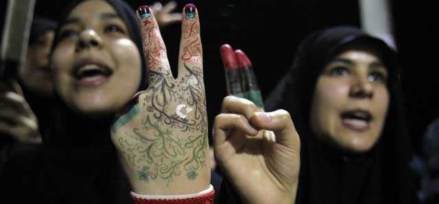 Jóvenes libias muestran la bandera tricolor pintada en sus manos, en los festejos de Trípoli. | Efe