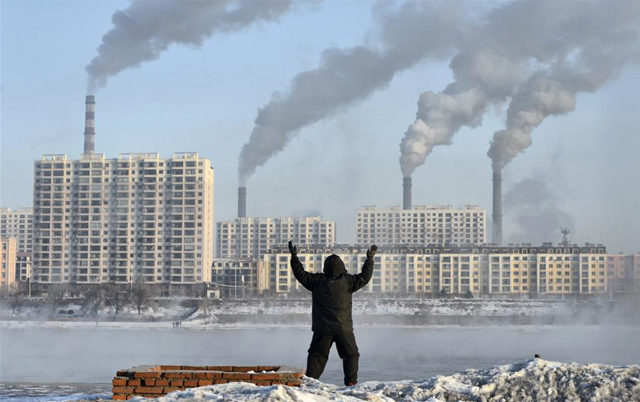 Un anciano hace ejercicios frente a unas fábricas en Jilin, China. | Reuters