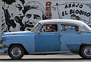 Un coche circula frente a un mural por las calles de la Habana (Foto: Desmond Boylan)