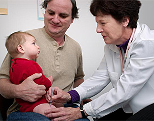 Un niño recibe una vacuna en brazos de su padre (Foto: CDC | Judy 
Schmidt)