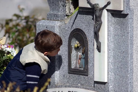 Un niño besa una lápida en un cementerio