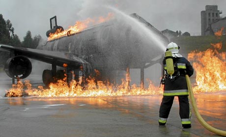 Un bombero apaga las llamas de un avión durante la realización de un simulacro| AENA
