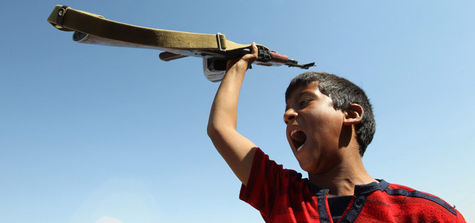 Un joven seguidor de Gadafi, grita consignas sosteniendo un rifle en Libia. | Efe