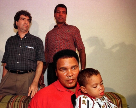 Ali coge en brazos al hijo del boxeador cubano Teofilo Stevenson ante el director de cine Edward Agner, a su llegada a Cuba con un cargamento de medicinas en 1998. (AP).